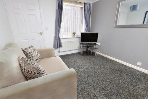a living room with a couch and a television at Witton House in Stockton-on-Tees