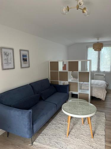 ein Wohnzimmer mit einem blauen Sofa und einem Tisch in der Unterkunft DisneylandParis Cosy indépendance in Chalifert