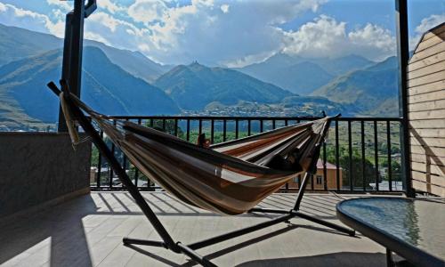 a hammock on a balcony with a view of mountains at Best view Kazbegi in Stepantsminda