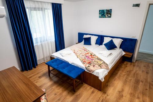 a bedroom with a blue and white bed and a table at Sole Boutique in Râmnicu Vâlcea