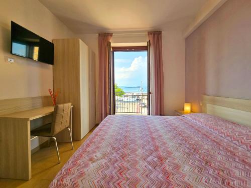 a bedroom with a bed and a desk and a window at Terrazza Vista Lago in Capodimonte
