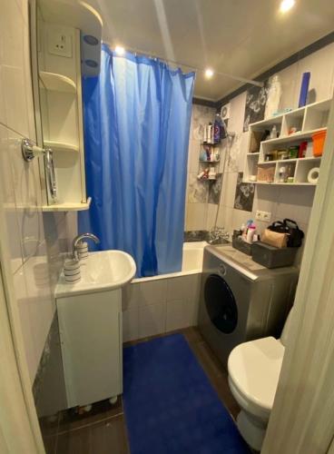 ein Badezimmer mit einem WC-Waschbecken und einem blauen Duschvorhang in der Unterkunft Nelwood Apartment in Socorro