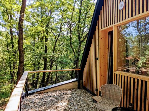 a cabin with a balcony with a window and two chairs at A Hely in Kismaros