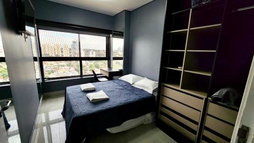 a small bedroom with a blue bed and a window at Loft Família c/ 2 Quartos e Lava e Seca no Vertigo in Campo Grande