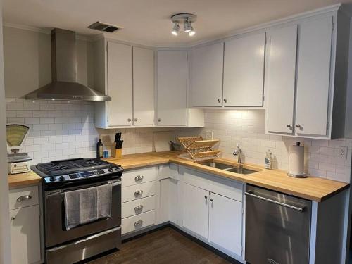 a kitchen with white cabinets and stainless steel appliances at Cute ranch house, less than 1 mile to downtown and skidmore. 2 miles to the track and SPAC in Saratoga Springs