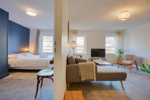 une chambre avec un lit et un salon avec un canapé dans l'établissement Le repère de Poincaré, à Nancy