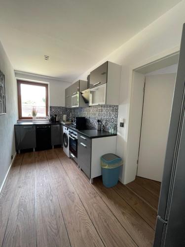 a kitchen with white cabinets and a wooden floor at MYSTAY BERLIN Müggelheim in Berlin