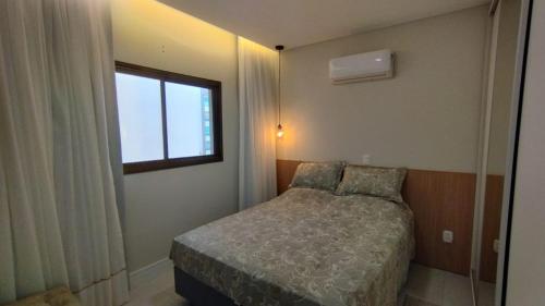 a small bedroom with a bed and a window at Departamento en Bombhinas in Bombinhas