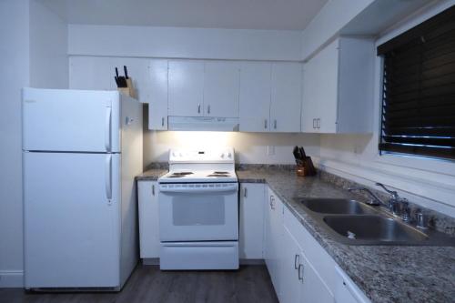 a white kitchen with a white refrigerator and a sink at 410 E 45th Unit 1 in Anchorage