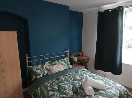 een slaapkamer met een bed met een blauwe muur bij Beautiful Town Centre home in Middlesbrough