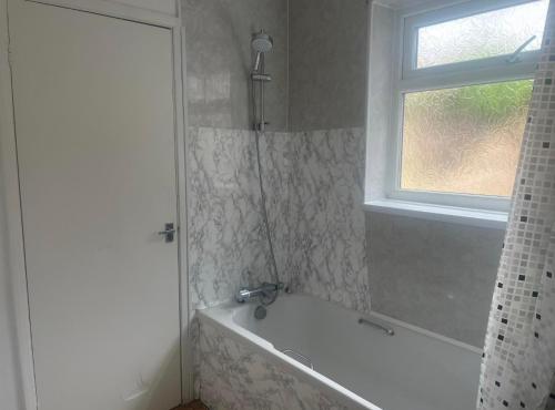 een badkamer met een wit bad en een raam bij Beautiful Town Centre home in Middlesbrough