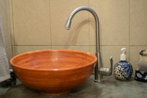 a bathroom sink with a wooden bowl and a faucet at Casa Punta Perula VILLAS in Pérula