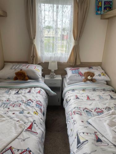 two beds in a bedroom with two teddy bears on them at 6 berth caravan Cherry tree holiday park Great yarmouth in Belton