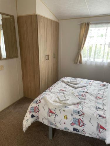 a bedroom with a bed with a comforter on it at 6 berth caravan Cherry tree holiday park Great yarmouth in Belton