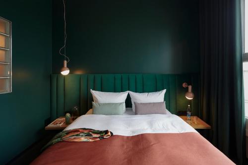1 dormitorio con 1 cama grande y pared verde en Basecamp Hotel Dortmund, en Dortmund