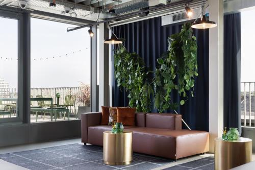 a living room with a couch and a plant at Basecamp Hotel Dortmund in Dortmund
