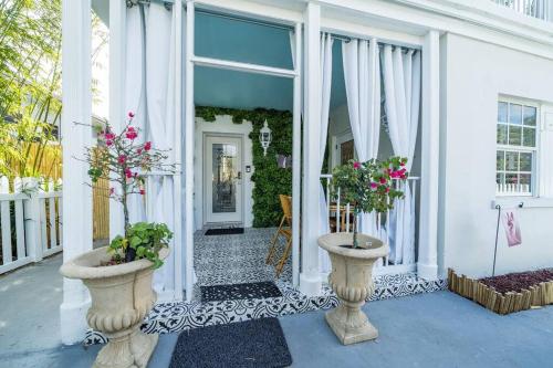 a white house with two vases with flowers in it at The Golden Alligator 2 - 3 beds 1 bath Palm Beach Regency style, near everything in West Palm Beach