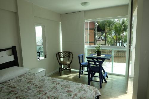 1 dormitorio con 1 cama, mesa y sillas en Hostel Toca da Moréia Bombinhas, en Bombinhas