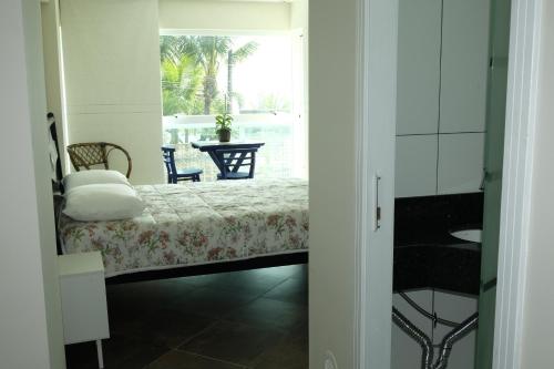 a bedroom with a bed and a view of a table at Hostel Toca da Moréia Bombinhas in Bombinhas