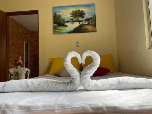 Dos cisnes hechos de toallas en una cama en Cantinho Casa Grande, en Beberibe