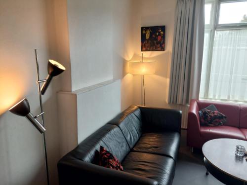 - un salon avec un canapé en cuir et une table dans l'établissement Sesimbra Domburg, à Domburg