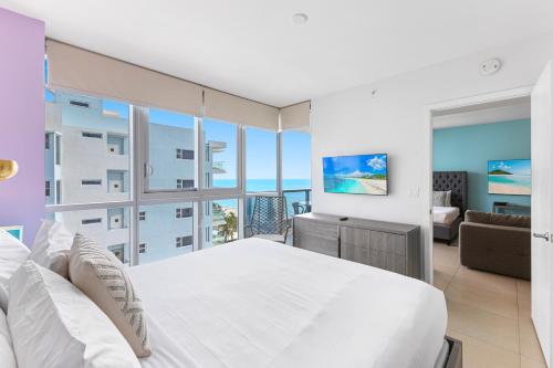 a bedroom with a large white bed and a living room at Dharma Home Suites Miami Beach at Monte Carlo in Miami Beach