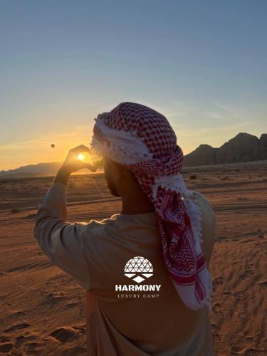 a woman standing in the desert looking at the sunset at Harmony Luxury Camp in Wadi Rum
