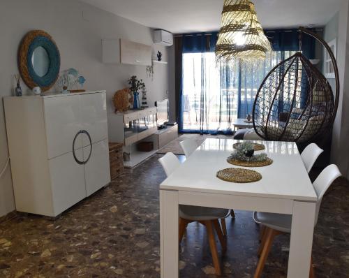 a kitchen and dining room with a white table and chairs at 1a. Línea, vistas al mar, acceso directo a playa y piscina in Salou