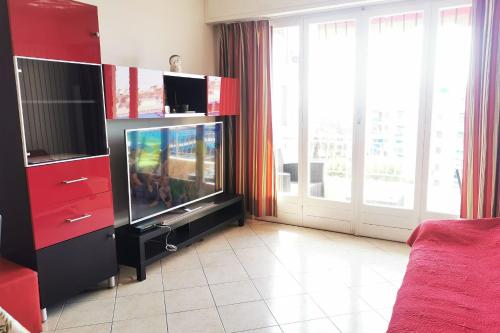 ein Wohnzimmer mit einem TV und einem roten Unterhaltungszentrum in der Unterkunft Charming 2-bedroom apartment Epsom B air-conditioned with parking in Cagnes-sur-Mer