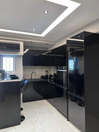 a large kitchen with black cabinets and a ceiling at The Absolute Luxury Apartment in Kalamata