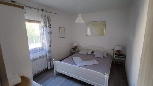 a bedroom with a white bed and a window at Villa Pagar - with jacuzzi - Renovated in 2022 in Povljana
