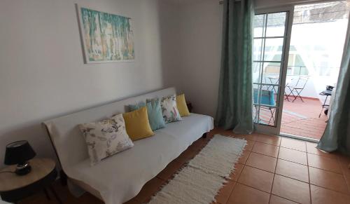 a living room with a white couch with pillows at Casa do Beco, confortável, em bairro típico de Olhão in Olhão