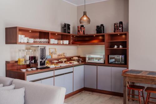 a kitchen with white and wooden cabinets and a table at Pousada João e Maria Gramado in Gramado