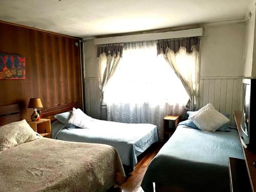 Habitación de hotel con 2 camas y ventana en Hospedaje Centro Valdivia, en Valdivia