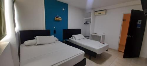 a small room with two beds and a blue wall at HOTEL TORREON AV in Neiva