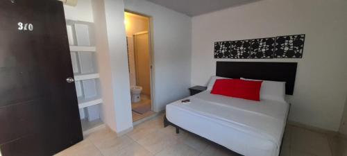 a bedroom with a white bed with a red pillow at HOTEL TORREON AV in Neiva