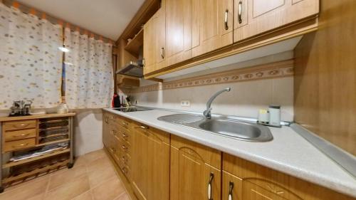 eine Küche mit einer Spüle und Holzschränken in der Unterkunft Casa Rural Rincones de Albares in Albares