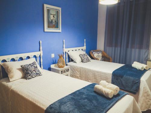 2 Betten in einem Zimmer mit blauen Wänden in der Unterkunft Casa Rural Rincones de Albares in Albares
