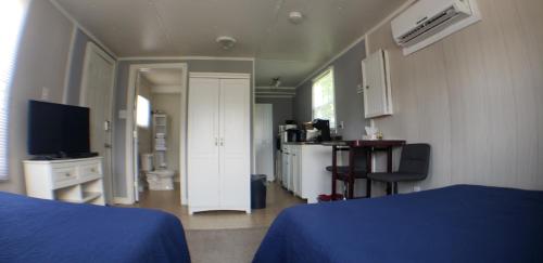um quarto com uma cama azul e uma televisão em Capeway Extended Stay Lodge em Port Hastings