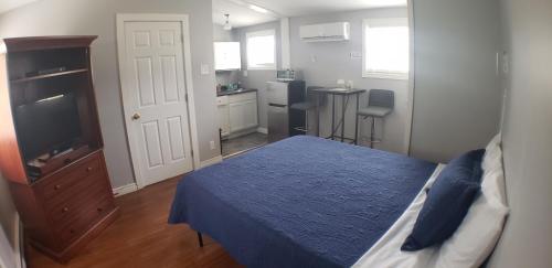 a bedroom with a bed and a tv and a kitchen at Capeway Extended Stay Lodge in Port Hastings
