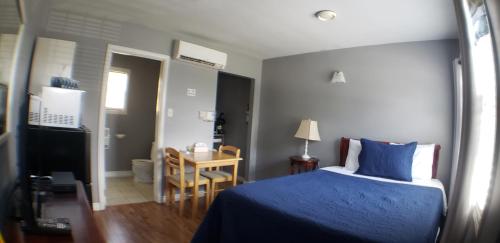 um quarto com uma cama azul e uma pequena mesa em Capeway Extended Stay Lodge em Port Hastings