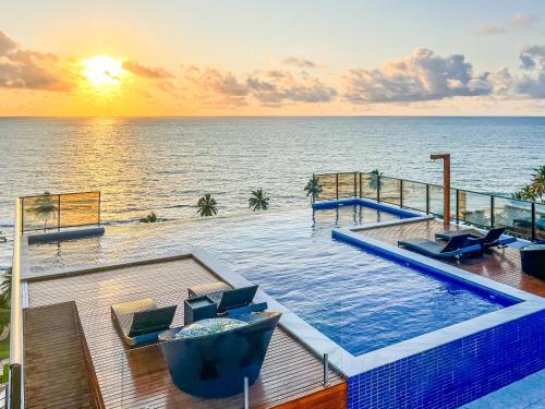 a swimming pool with the ocean in the background at FLATS ENSEADA Do SOL in Jacumã