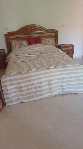 a large bed with a wooden headboard in a bedroom at Bel appartement in Oujda