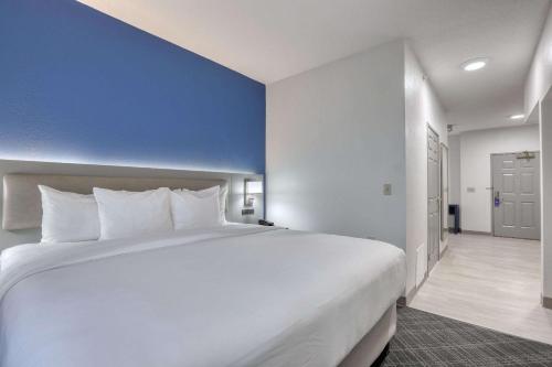 a large white bed in a room with a blue wall at Comfort Suites Milwaukee Airport in Oak Creek