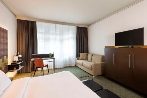 ein Hotelzimmer mit einem Bett und einem TV in der Unterkunft NH Bern The Bristol in Bern
