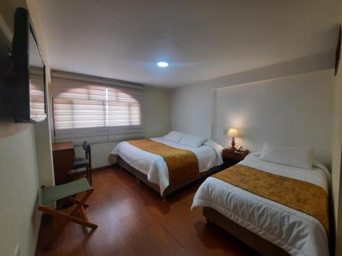 a hotel room with two beds and a window at Hotel El Lago in Paipa