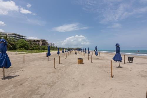 a row of blue umbrellas on a beach at Lujoso Apartamento Con Salida Directa A La Playa Edificio Morros Eco in Cartagena de Indias