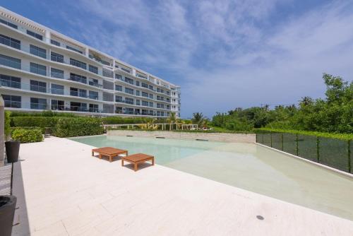 a swimming pool with two benches and a building at Lujoso Apartamento Con Salida Directa A La Playa Edificio Morros Eco in Cartagena de Indias