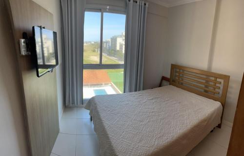 Un dormitorio con una cama y una ventana con piscina. en MANDAI FLAT 412, en Cabo Frío