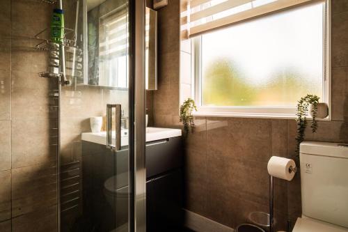 een badkamer met een toilet, een wastafel en een raam bij Luxury Affordable Business Stay with Hot Tub and Pool Table in Enfield Lock